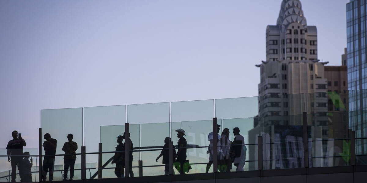 People cross a pedestrian bridge along the Las Vegas Strip during Labor Day weekend on Sunday, ...
